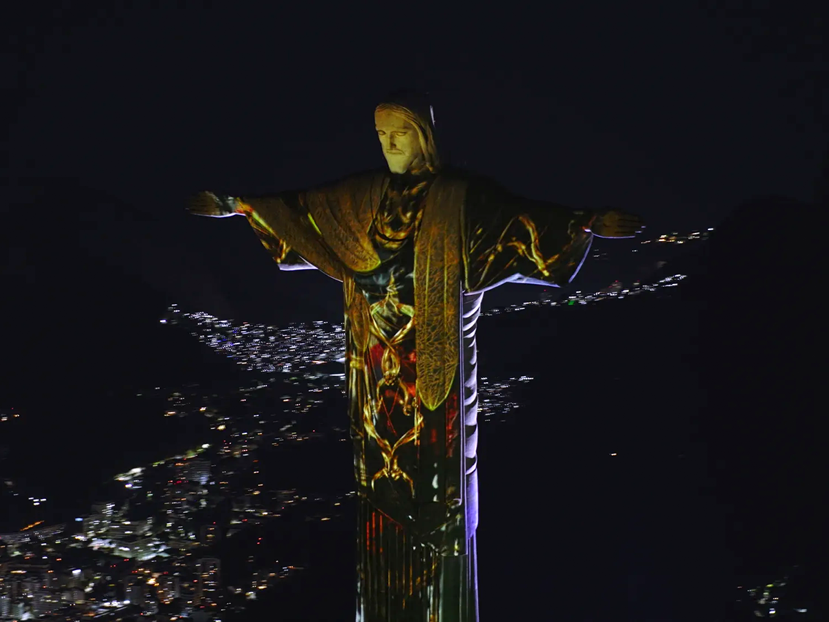 Proje&ccedil;&atilde;o mapeada da Miss&atilde;o Econ&ocirc;mica Belga no Cristo Redentor, com grafismos dourados e tecnologia Barco