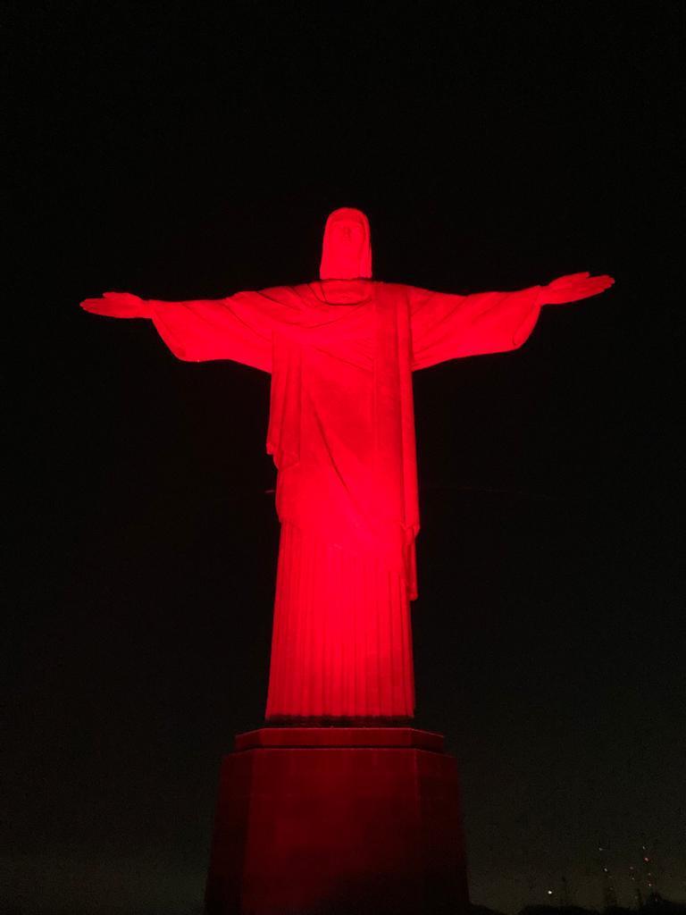 Cristo Redentor iluminado na cor vermelha pela campanha “Siga Seu Coração”